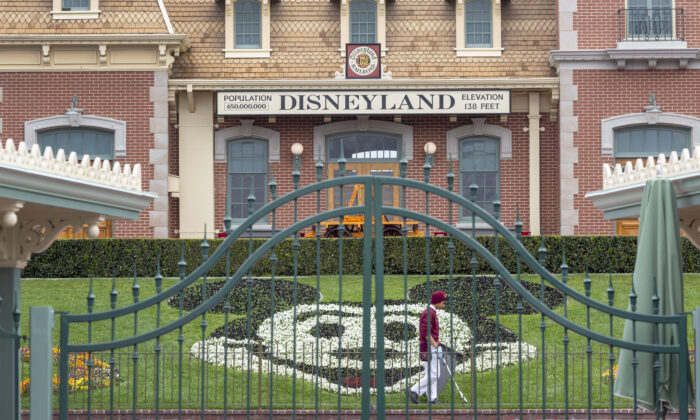 Un empleado limpia los terrenos detrás de las puertas cerradas de Disneyland Park, el primer día del cierre, en Anaheim, California, el 14 de marzo de 2020. (David McNew/AFP a través de Getty Images)