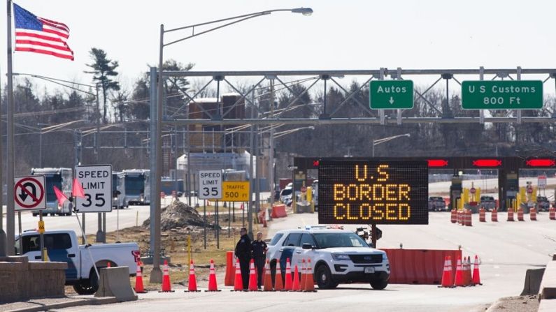 Los oficiales de aduanas de EE.UU. se paran junto a un cartel que dice que la frontera de EE.UU. está cerrada en la frontera entre EE.UU. y Canadá en Lansdowne, Ontario, el 22 de marzo de 2020. (LARS HAGBERG/AFP vía Getty Images)
