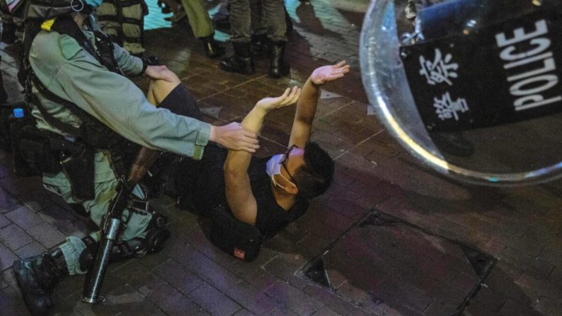 Un oficial de policía detiene a un hombre cuando los manifestantes se reunieron en el distrito Mong Kok de Hong Kong el 12 de junio de 2020. (Isaac Lawrence/AFP a través de Getty Images)