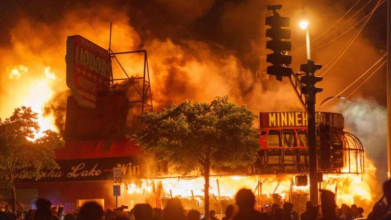 Los manifestantes se reúnen frente a una tienda de licores en llamas cerca del Tercer Recinto Policial en Minneapolis, Minnesota, el 28 de mayo de 2020. (Kerem Yucel/AFP a través de Getty Images)