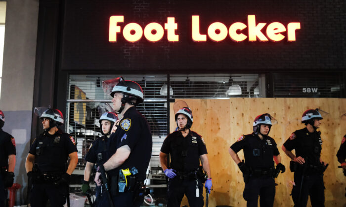 La policía hace guardia cerca de tiendas saqueadas durante una noche de protestas y vandalismo por la muerte de George Floyd en la ciudad de Nueva York el 1 de junio de 2020. (Spencer Platt/Getty Images)
