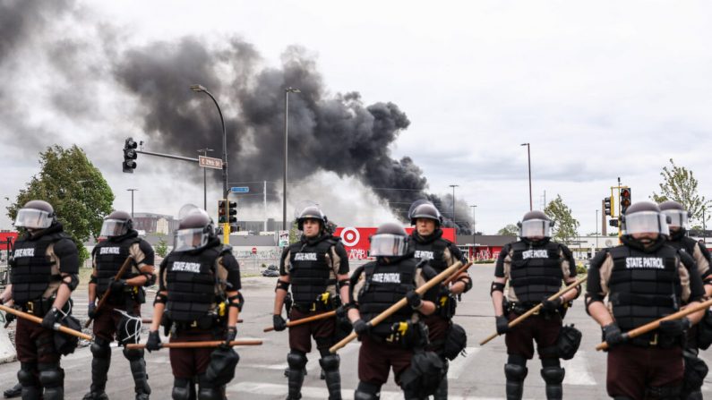 La policía estatal hace guardia mientras las olas de humo de los edificios siguen ardiendo tras una noche de protestas y violencia tras la muerte de George Floyd, en Minneapolis, Minnesota, el 29 de mayo de 2020. (Charlotte Cuthbertson/The Epoch Times)