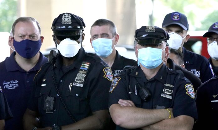 Los oficiales de policía de NYPD escuchan mientras la Asociación de Beneficencia Policial de la Ciudad de Nueva York, el presidente Pat Lynch y representantes de otros sindicatos de NYPD y de la aplicación de la ley celebran una conferencia de prensa en el estacionamiento del Estadio Icahn para tratar el "actual ambiente anti-aplicación de la ley" en la ciudad de Nueva York el 9 de junio de 2020. (Timothy A. Clary/AFP vía Getty Images)