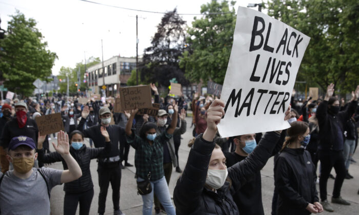 Las personas sostienen pancartas para protestar por la muerte de George Floyd, frente al Recinto Este del Departamento de Policía de Seattle, en Seattle, Washington, el 2 de junio de 2020. (Jason Redmond/AFP a través de Getty Images)
 
