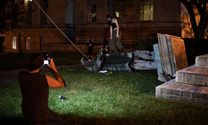 La gente se para y toma fotos con la estatua del general confederado Albert Pike después de que fue derribada por los manifestantes en la plaza del Poder Judicial en Washington a fines del 19 de junio de 2020. (ERIC BARADAT / AFP vía Getty Images)