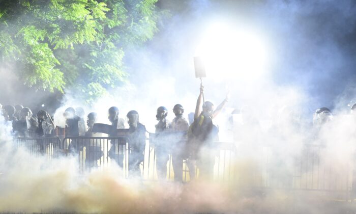 El humo se eleva alrededor de un manifestante que levanta las manos frente a una fila de policías durante una manifestación en contra de la muerte de George Floyd en un parque cerca a la Casa Blanca en Washington el 31 de mayo de 2020. (Roberto Schmidt/AFP vía Getty Images)