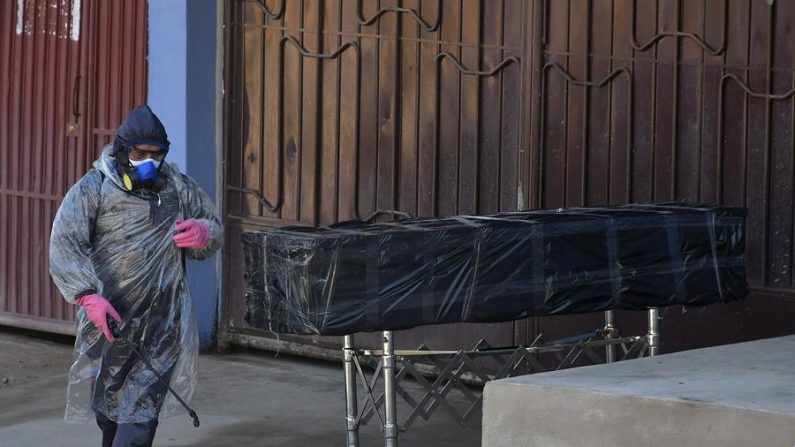 Empleados de una funeraria retiran el cuerpo sin vida de un hombre que permaneció durante horas abandonado en una calle, este domingo en Cochabamba (Bolivia). EFE/Jorge Ábrego
