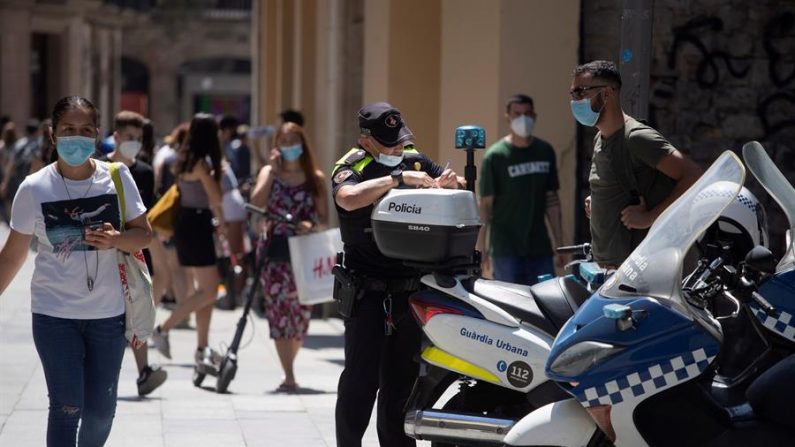 Un policía multa a un ciclista por una infracción cometida y le advierte también de la obligatoriedad de llevar mascarilla cuando se viaja, el 11 de julio de 2020 en el centro de Barcelona, Cataluña, España. EFE/Marta Pérez
