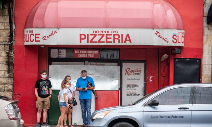 Una familia con mascarillas se para frente a una pizzería en Austin, Texas, el 26 de junio de 2020. (Sergio Flores/AFP a través de Getty Images)