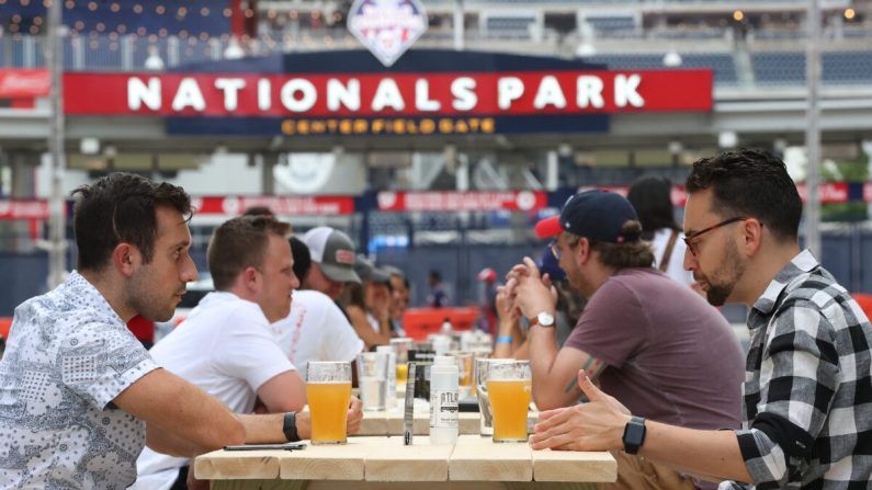 Los aficionados al béisbol beben cerveza mientras se reúnen en las afueras del Parque Nacional durante el partido del día de la inauguración entre los Nationals de Washington y los Yankees de Nueva York en el Distrito de Columbia el 23 de julio de 2020. (Win McNamee/Getty Images)