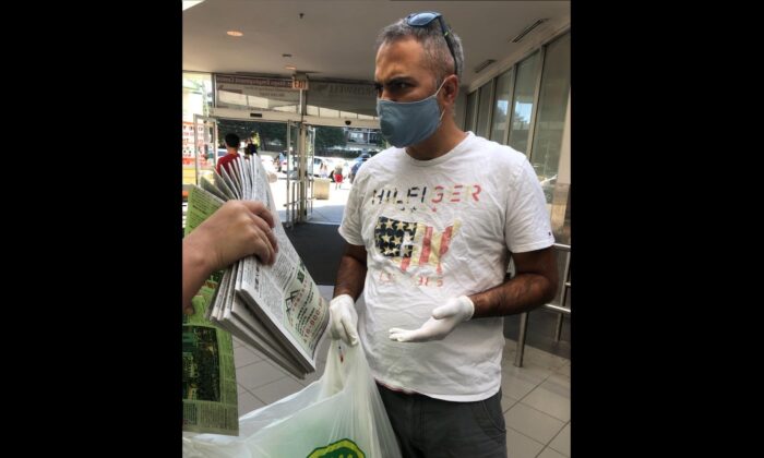 Un miembro del personal de La Gran Época se enfrenta a un hombre (no se ve en el cuadro), después de que lo vieron tomando más de 10 copias del periódico La Gran Época de una ubicación en Toronto, el 4 de julio de 2020. (La Gran Época)