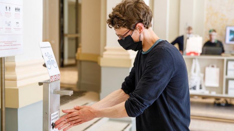 Una mujer con mascarilla se desinfecta las manos con gel hidroalcohólico antes de entrar en un museo en Viena (Austria). EFE/EPA/FLORIAN WIESER/Archivo