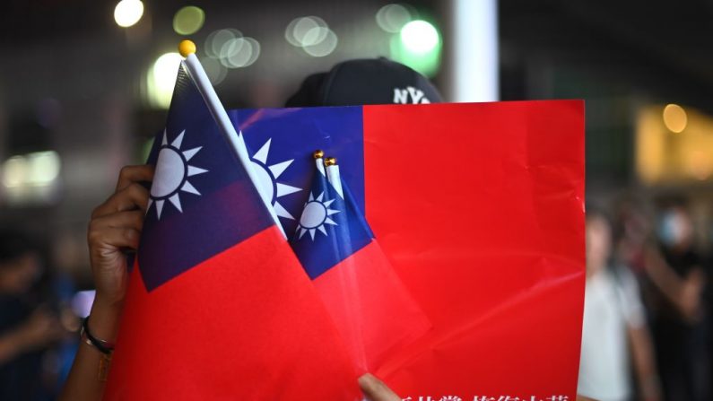 Un hombre sostiene banderas taiwanesas mientras se une a otros para asistir a un mitin para conmemorar el Día Nacional de Taiwán el 10 de octubre de 2019. (PHILIP FONG / AFP a través de Getty Images)