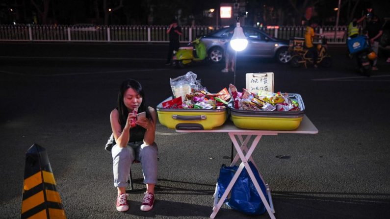Una vendedora ambulante espera a los clientes en la carretera frente a un centro comercial en Beijing, China, el 10 de junio de 2020. (GREG BAKER/AFP/Getty Images)