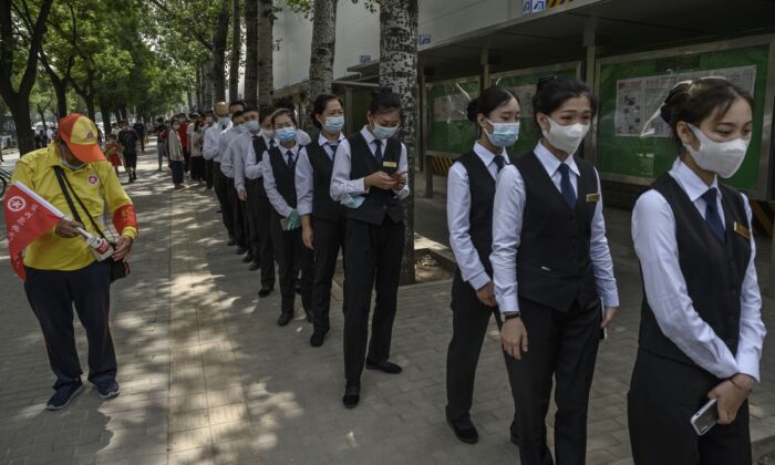 Trabajadores de la industria de servicios chinos hacen cola para las pruebas de hisopado de ácido nucleico para detectar COVID-19 en un lugar de exámenes en Beijing, China, el 1 de julio de 2020. (Kevin Frayer/Getty Images)