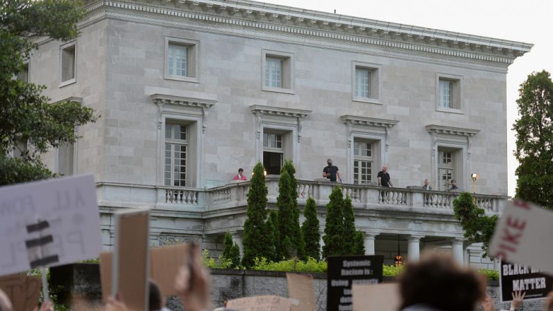 El personal de seguridad se encuentra en el balcón de la casa de Mark y Patricia McCloskey mientras los manifestantes protestan en su vecindario el 3 de julio de 2020 en St Louis, Missouri. (Michael B. Thomas/Getty Images)