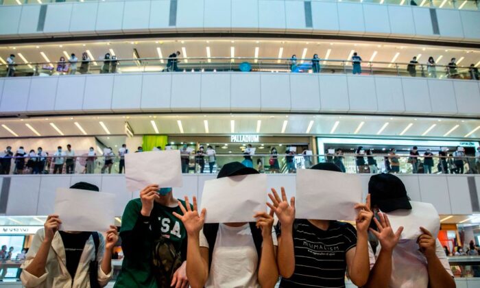 Los manifestantes sostienen papeles en blanco durante una manifestación en un centro comercial en Hong Kong, el 6 de julio de 2020. (Isaac Lawrence/AFP a través de Getty Images)