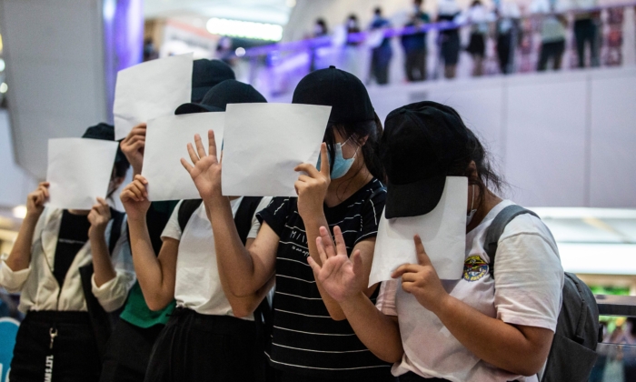 Los manifestantes sostienen documentos en blanco durante una manifestación en un centro comercial en Hong Kong el 6 de julio de 2020, en respuesta a una nueva ley de seguridad nacional introducida en la ciudad que hace que las opiniones políticas, los lemas y los letreros que abogan por la independencia o liberación de Hong Kong sean ilegales. (Isaac Lawrence/AFP a través de Getty Images)
