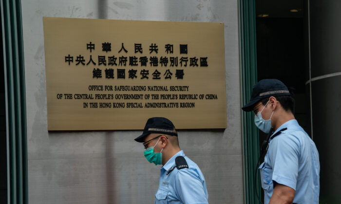 Oficiales de policía pasan por delante de una placa en las afueras de la nueva oficina de seguridad nacional de Beijing después de su inauguración oficial en Hong Kong, el 8 de julio de 2020. (Anthony Kwan/Getty Images)