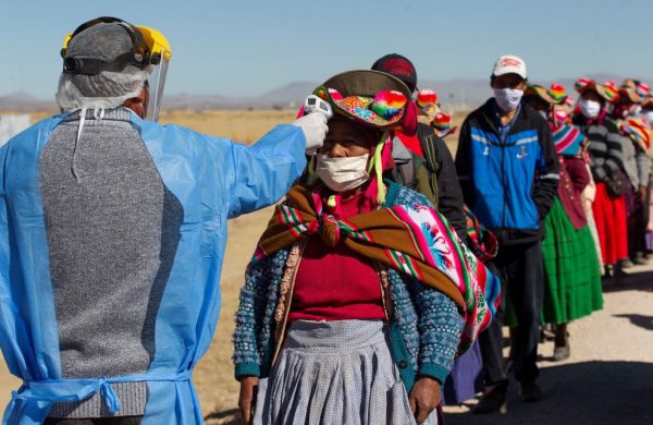 Un trabajador de la salud comprueba la temperatura a los residentes de las comunidades vecinas que se dirigen al mercado semanal de alimentos en Coata (Perú), a 40 km de Puno y cerca de la frontera con Bolivia el 8 de julio de 2020. (Foto de CARLOS MAMANI/AFP vía Getty Images)