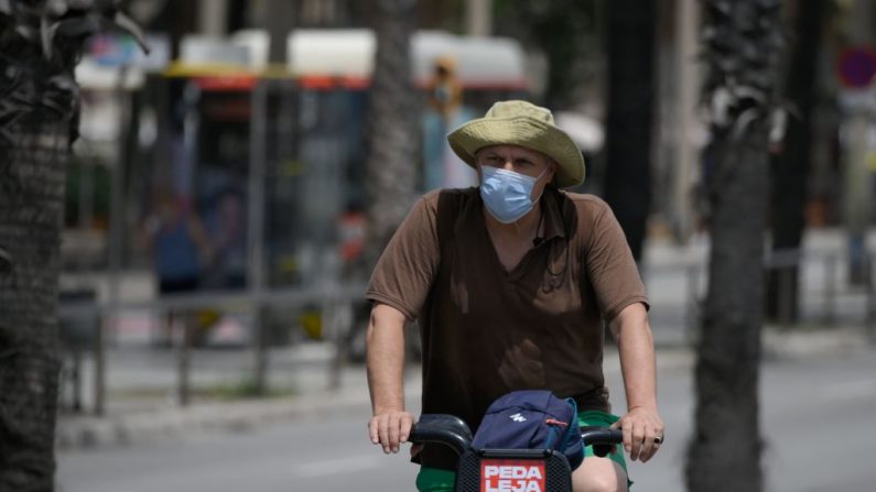 Un hombre con una máscara facial monta una bicicleta cerca de la playa de la Barceloneta en Barcelona (España) el 9 de julio de 2020. (Foto de LLUIS GENE/AFP vía Getty Images)