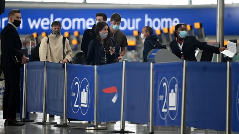 Pasajeros con mascarillas debido a la pandemia de COVID-19, hacen fila en un mostrador de facturación de British Airways en el aeropuerto de Heathrow, al oeste de Londres (Inglaterra), el 10 de julio de 2020. (Foto de DANIEL LEAL-OLIVAS/AFP a través de Getty Images)