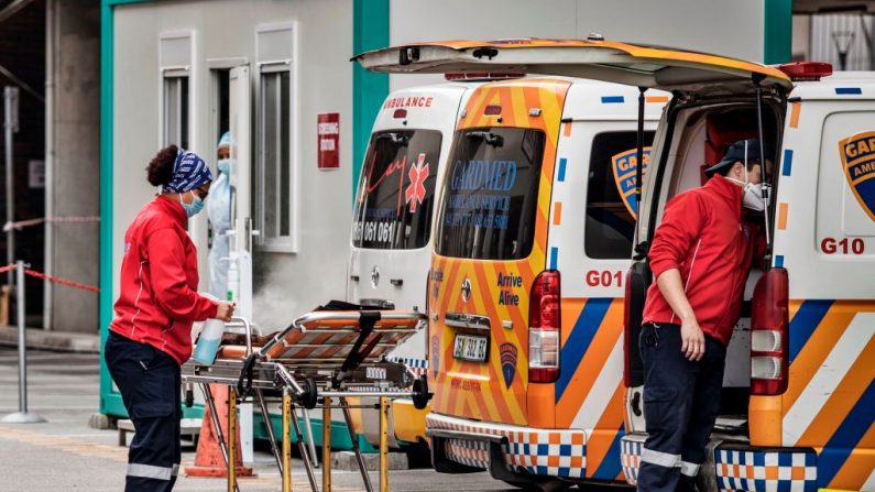 Un miembro de la tripulación de una ambulancia higieniza una camilla en las urgencias del Hospital Greenacres de Port Elizabeth (Sudáfrica), el 10 de julio de 2020 cerca de una fila de ambulancias en cola. (Foto de MARCO LONGARI/AFP vía Getty Images)