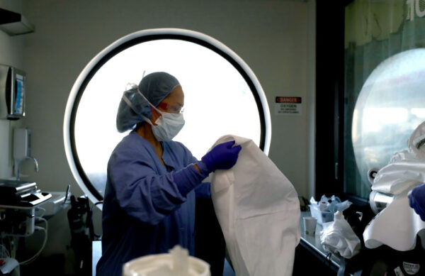 Una enfermera limpia el equipo de protección personal (PPE) después de formar parte de un equipo que realizó un procedimiento a un paciente con COVID-19 en el Centro Médico Regional en San José, California, el 21 de mayo de 2020. (Justin Sullivan/Getty Images)