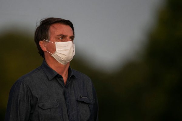 El presidente brasileño Jair Bolsonaro se pone una máscara facial frente a la residencia oficial después de dar positivo en el test de COVID-19 en el Palacio Alvorada el 15 de julio de 2020 en Brasilia, Brasil. (Foto de Bruna Prado/Getty Images)