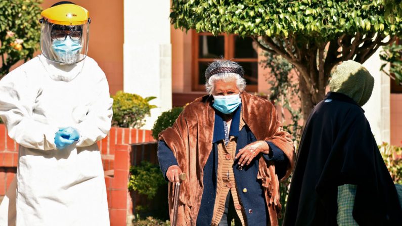 Un trabajador de la salud camina junto a una anciana para que le hagan la prueba de COVID-19 en el asilo de ancianos de San José en Cochabamba, Bolivia, el 17 de julio de 2020. (Foto por AFP vía Getty Images)