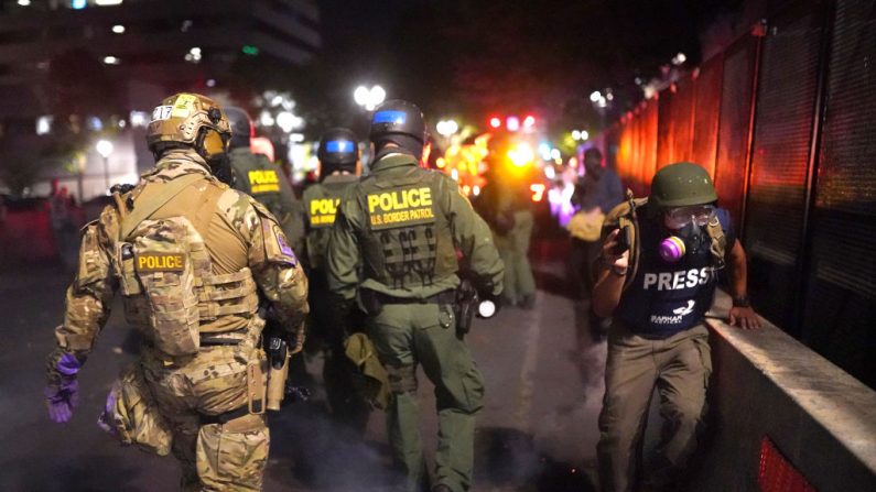 Un periodista pasa frente a los oficiales federales, el 30 de julio de 2020, en Portland, Oregon. (Nathan Howard/Getty Images)