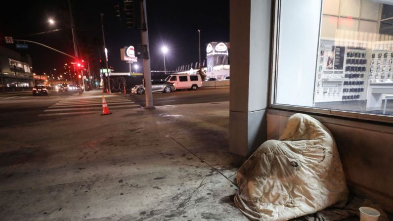 Una persona sin hogar descansa debajo de una manta en Sunset Boulevard, en medio de la pandemia COVID-19, en Los Ángeles el 1 de julio de 2020. (Mario Tama / Getty Images)

