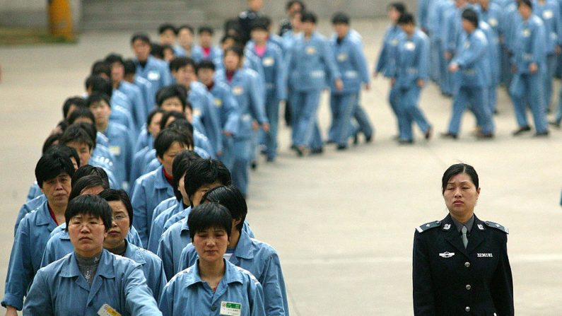 Prisioneras caminan al lado de una escolta policial durante una jornada de apertura de la prisión en Nanjing, 11 de abril de 2005, en el este de China. (STR/AFP a través de Getty Images)