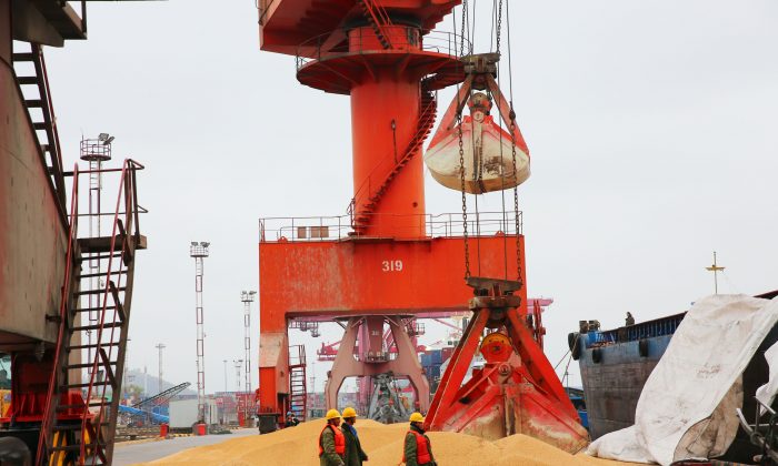 Los trabajadores pasan frente a la soja importada en un puerto, en la ciudad de Nantong, provincia de Jiangsu, el 4 de abril de 2018. (AFP/Getty Images)