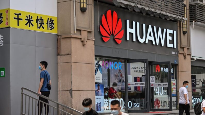 Personas con mascarillas pasan por delante de una tienda Huawei en Wuhan, en el centro de la provincia china de Hubei, el 26 de mayo de 2020. (HECTOR RETAMAL/AFP vía Getty Images)

