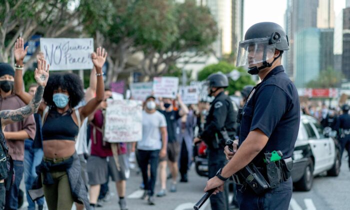 Los manifestantes pasan frente a los oficiales de LAPD durante una manifestación sobre la muerte de George Floyd, en Los Ángeles, California, el 6 de junio de 2020. (Kyle Grillot / AFP a través de Getty Images)