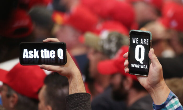 Las personas sostienen teléfonos inteligentes con mensajes relacionados con QAnon en exhibición, en un mitin en Las Vegas, Nevada, el 21 de febrero de 2020. (Mario Tama / Getty Images)