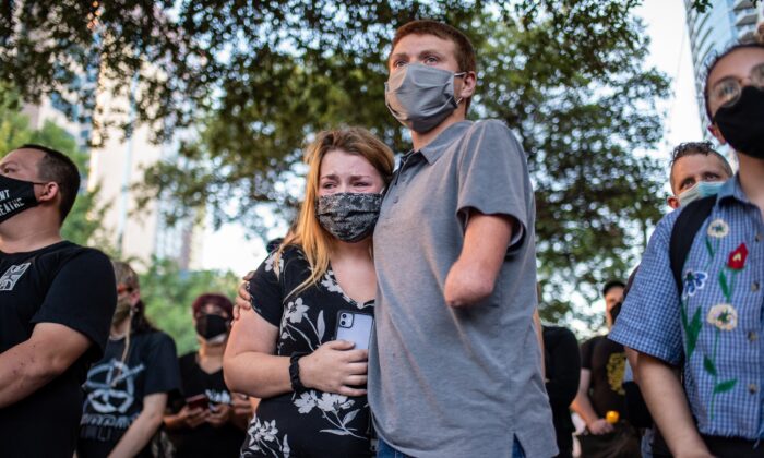 Anna Mayo, la hermana de Garrett Foster, abraza a su marido Chase Mayo en una vigilia por su hermano en el centro de Austin, Texas, el 26 de julio de 2020. (Sergio Flores/Getty Images)