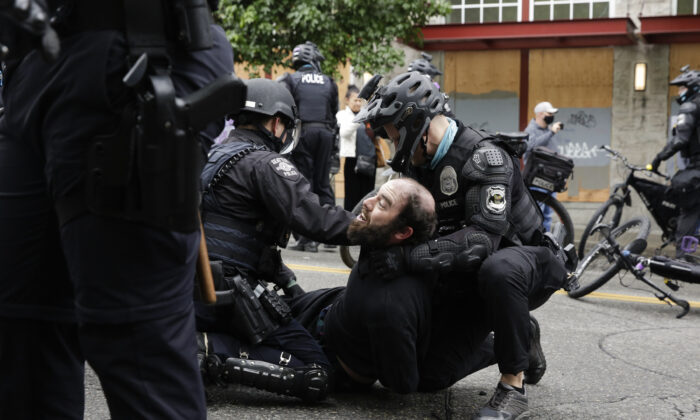 Policía de Seattle arresta a un manifestante que bloqueaba la intersección de la calle East Pine y la 11ª Avenida, cuando la ciudad retoma la zona de protesta ocupada de Capitol Hill (CHOP) en Seattle el 1 de julio de 2020. (Jason Redmond/AFP a través Getty Images)

