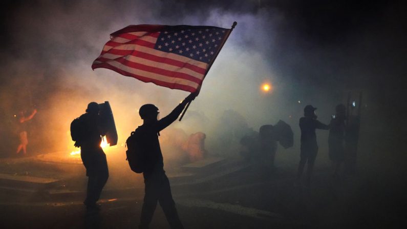 Un manifestante enarbola una bandera estadounidense mientras camina a través de gas lacrimógeno disparado por agentes federales durante una protesta frente a la corte de Estados Unidos Mark O. Hatfield el 21 de julio de 2020 en Portland, Oregon. (Nathan Howard/Getty Images)