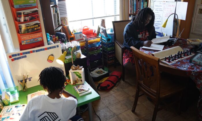 Ayinde (Izq.), de 10 años, y Zion, de 17, hacen su trabajo escolar en su casa de Washington, el 24 de febrero de 2017. (MANDEL NGAN/AFP vía Getty Images)