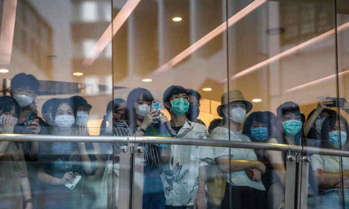 Varios transeúntes observan desde un puente a los manifestantes que participan en un mitin contra una nueva ley de seguridad nacional en Hong Kong el 1 de julio de 2020. (Anthony Wallace/AFP vía Getty Images)