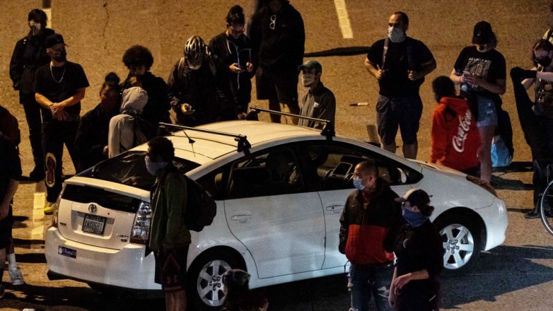 Los manifestantes rodean un coche mientras bloquean la Interestatal 5 después de marchar desde el área conocida como la Protesta Organizada de Capitol Hill (CHOP) el 24 de junio de 2020 en Seattle, Washington. (David Ryder/Getty Images)