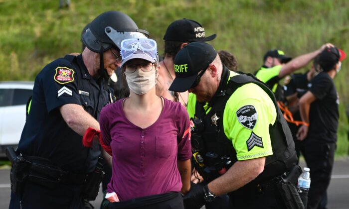 La policía arresta a una manifestante que ayudó a bloquear el camino hacia el Monumento Nacional Monte Rushmore en Keystone, Dakota del Sur, el 3 de julio de 2020. (Andrew Caballero-Reynolds / AFP a través de Getty Images)