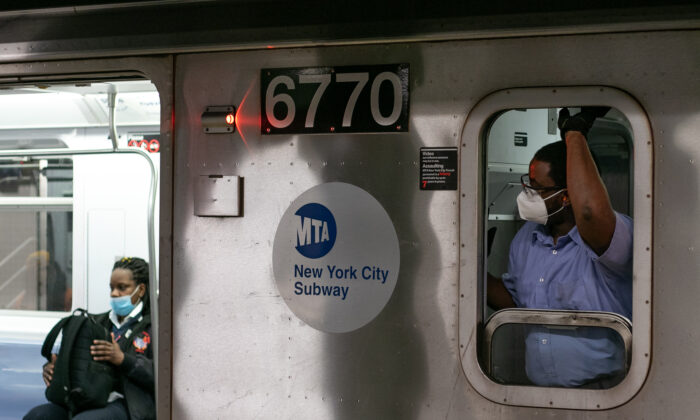 Un miembro del equipo del metro y un pasajero del tren usan máscaras protectoras en Manhattan, N.Y., el 4 de mayo de 2020. (Chung I Ho/The Epoch Times)