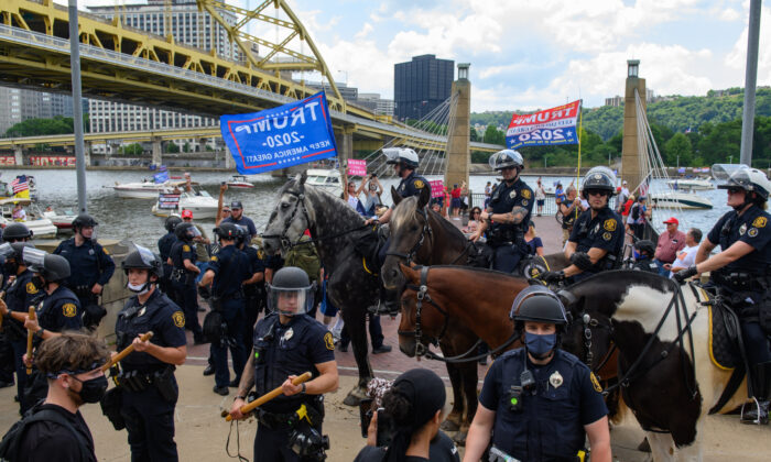 La policía antidisturbios de Pittsburgh interviene en un enfrentamiento entre un grupo de manifestantes de Black Lives Matter y un grupo de partidarios de Trump. El altercado se produjo cuando los simpatizantes del presidente esperaban un desfile de botes que apoyaban la reelección del actual presidente de EE.UU., el 4 de julio de 2020, en Pittsburgh, Pensilvania. (Jeff Swensen/Getty Images) 