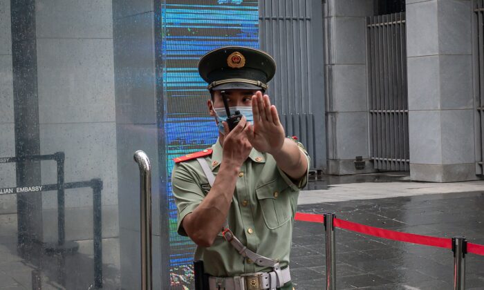 Un oficial de la policía paramilitar china hace un gesto y habla por su radio mientras está de pie en la puerta de entrada de la embajada de Australia, en Beijing el 9 de julio de 2020. (Nicolas Asfouri/AFP a través de Getty Images)