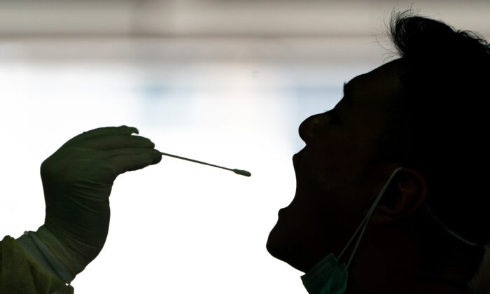 Un profesional médico está recogiendo una muestra de hisopo de un taxista para la prueba COVID-19 en una improvisada estación de pruebas en Hong Kong el 24 de julio de 2020. (Anthony Kwan/Getty Images)