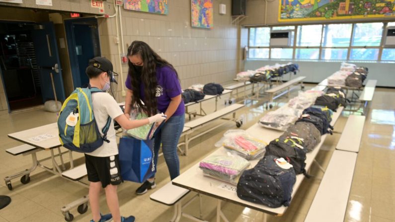 La maestra Aurora Chen entrega las pertenencias que se quedaron antes del cierre en las escuelas a un estudiante en la Escuela Yung Wing P.S. 124 de la ciudad de Nueva York, el 29 de junio de 2020. (Michael Loccisano/Getty Images)