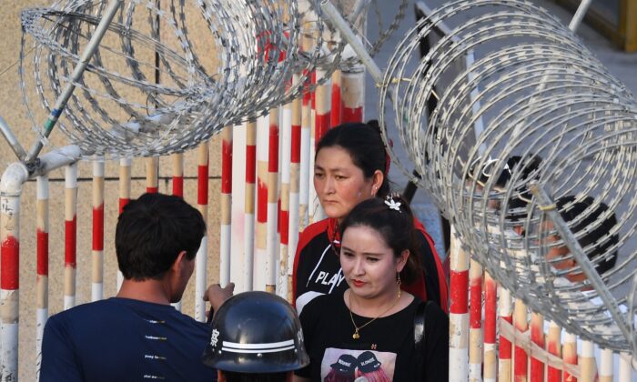 Esta foto tomada el 31 de mayo de 2019 muestra a una mujer uigur (C) atravesando la entrada de un bazar en Hotan, en la región noroccidental de China, Xinjiang. (Greg Baker/AFP vía Getty Images)